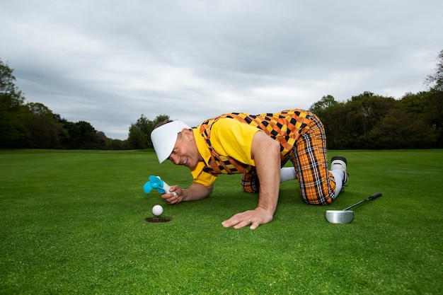 Free photo man having a game of golf outdoors on the course