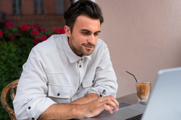 Man having an iced coffee break while using laptop