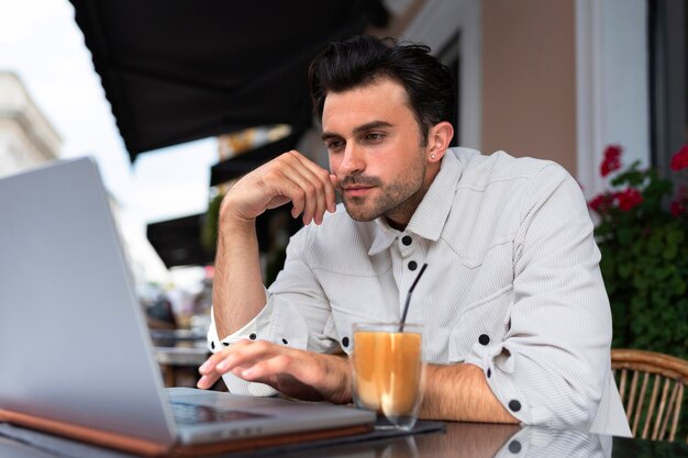 Man having an iced coffee break while using laptop