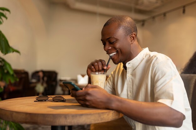 Man having an iced coffee break while using smartphone