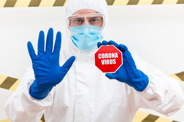 Man in hazmat suit with coronavirus stop sign