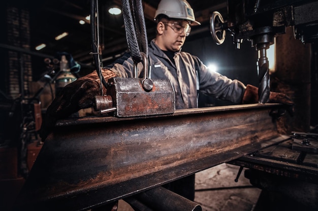 Free photo man in helmet is moving a piece of rail at metal factory.