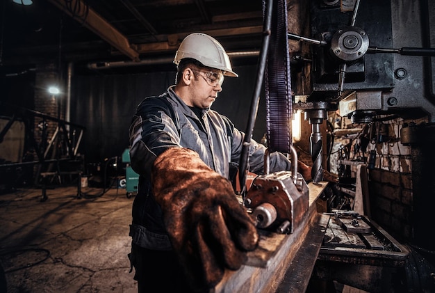 Free photo man in helmet is moving a piece of rail at metal factory.