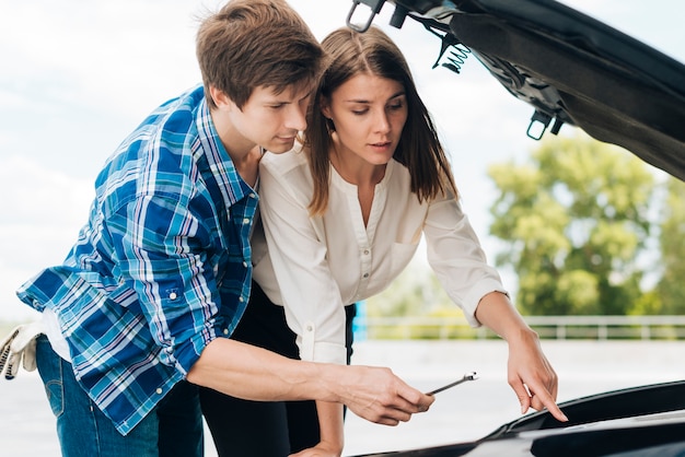 Man helping woman fix her car