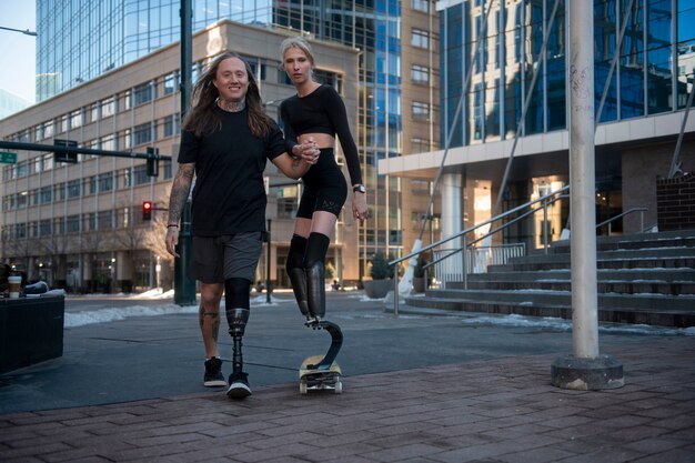 Man helping woman with leg disability skateboarding in the city