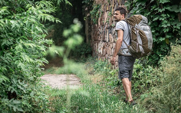 A man on a hike with a large backpack travels in the forest.