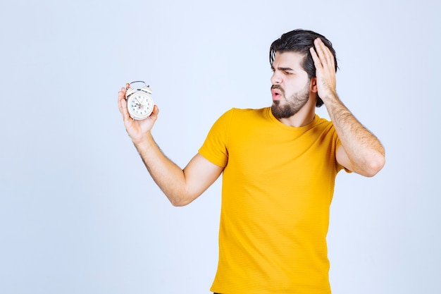 Man holding an alarm clock and noticed that he is late.