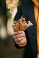 Free photo man holding autumn leave in the park