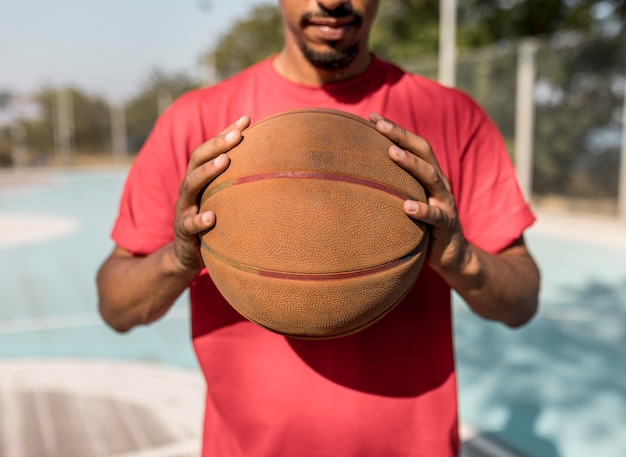 Free Photo man holding a basketball in front of him