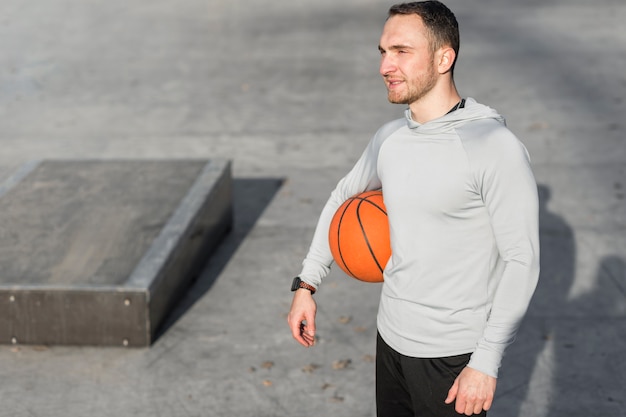 Man holding a basketball and looking away