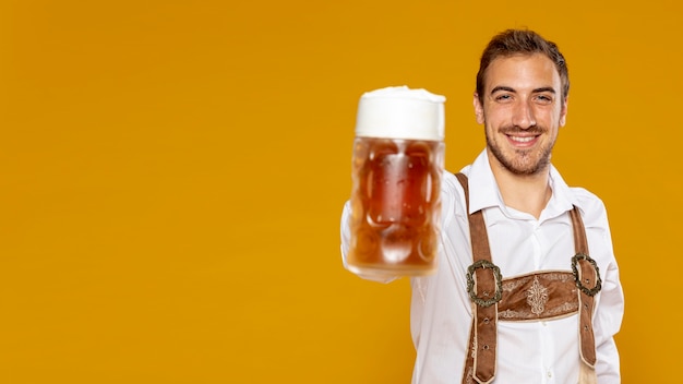 Free photo man holding beer pint with copy space