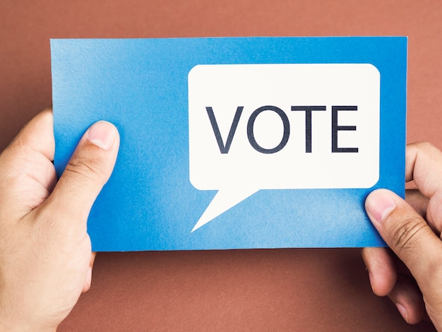 Man holding a blue card with a voting speech balloon