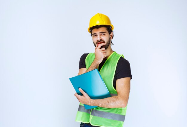 Man holding a blue folder and thinking.