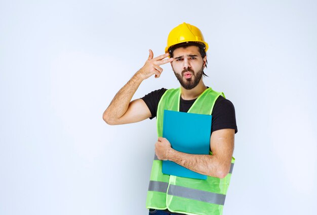 Man holding a blue folder and thinking.