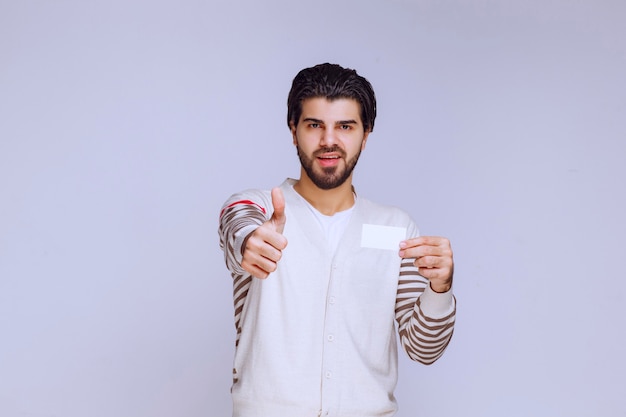 Man holding a business card and showing thumb up sign. 