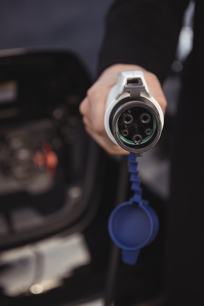 Man holding car charger at electric vehicle charging station