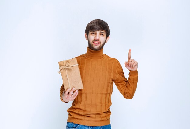 Man holding a cardboard gift box and pointing something in the upside.