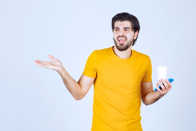 Free Photo man holding a coffee cup and giving presentation using open hand.