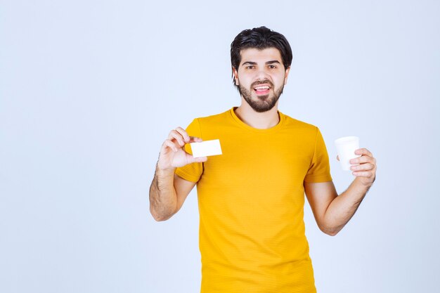 Man holding a coffee cup and presenting his business card.