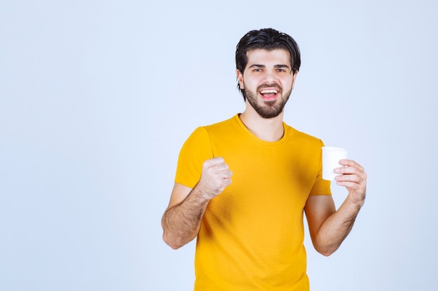 Free Photo man holding a coffee cup and showing his power.