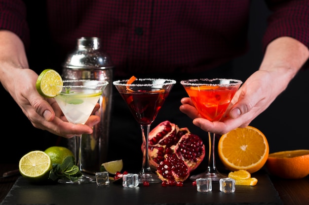 Free photo man holding colorful cocktail glasses