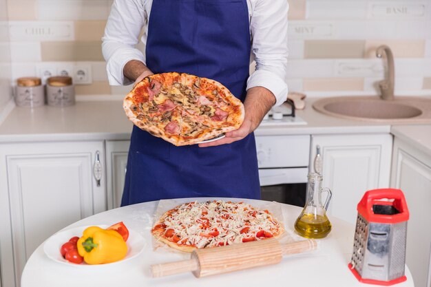 Man holding cooked pizza in hands 