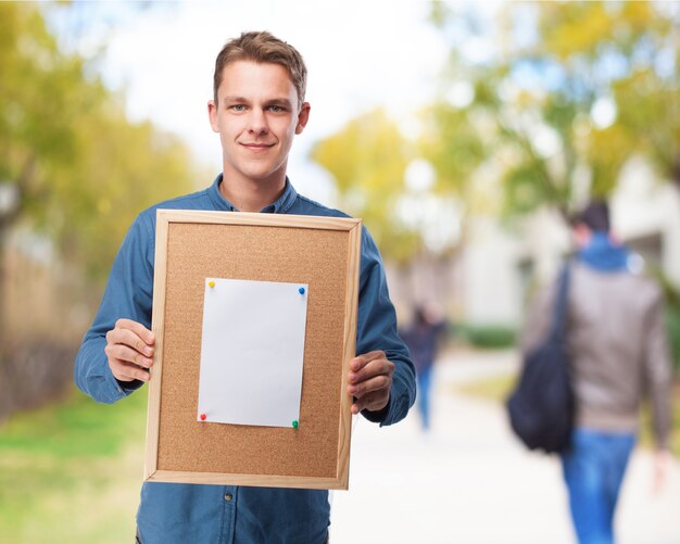 Man holding a cork bulletin board with a blank sheet