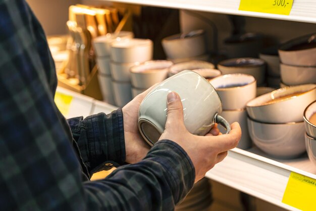 Man holding cup from a shelf in homeware store