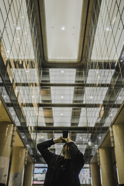 Man holding DSLR camera while taking photo in hallway