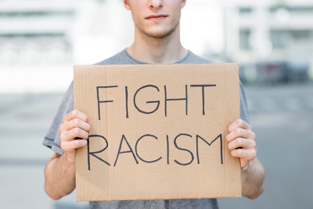 Free photo man holding fight racism quote on cardboard