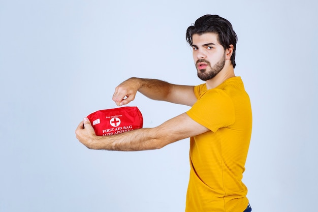 Free photo man holding a first aid kit and opening the zip.