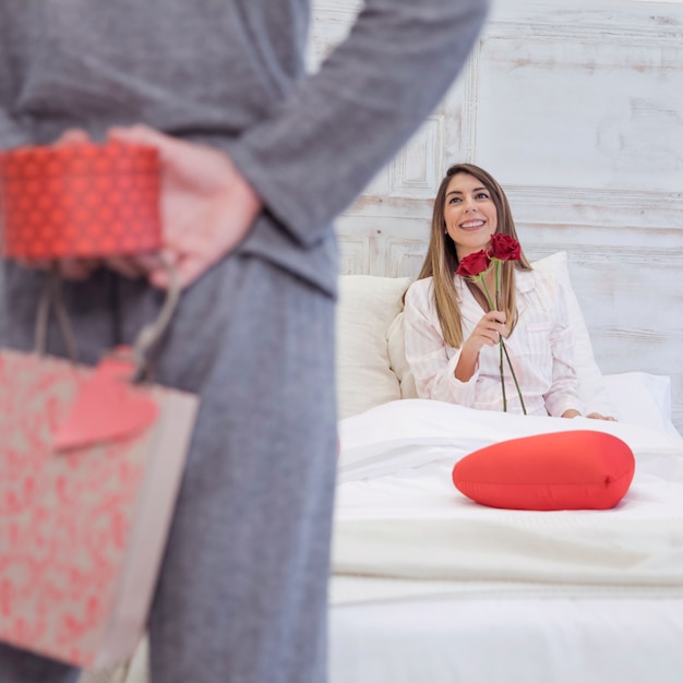 Free photo man holding gift box for woman behind back