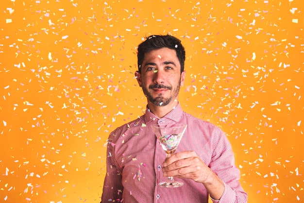 Free photo man holding a glass on orange background