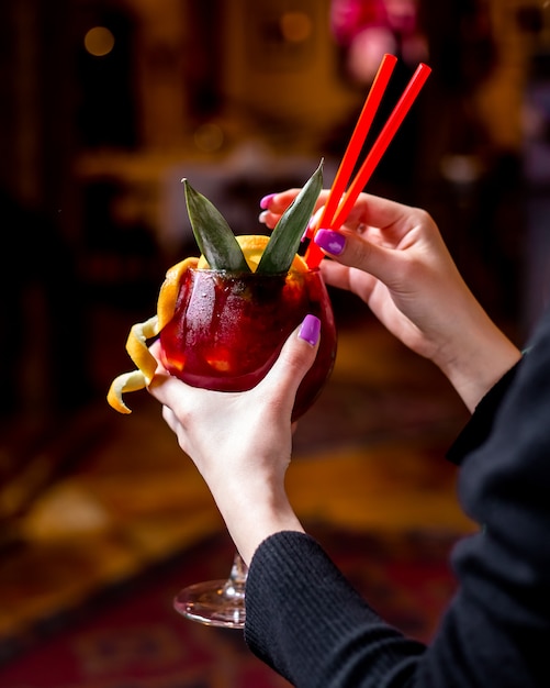 Man holding glass with berries cocktail with orange ice sparkling water cinnamon side view