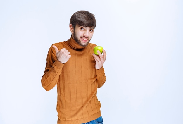 Man holding a green apple and showing thumb up.