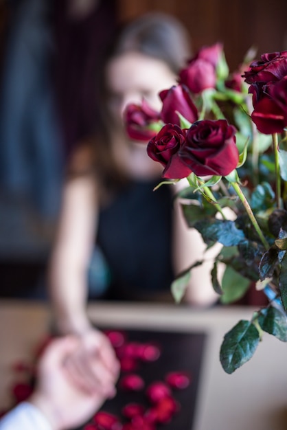 Free photo man holding hand of woman near bouquet of flowers