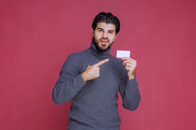 Man holding his business card and pointing at it.