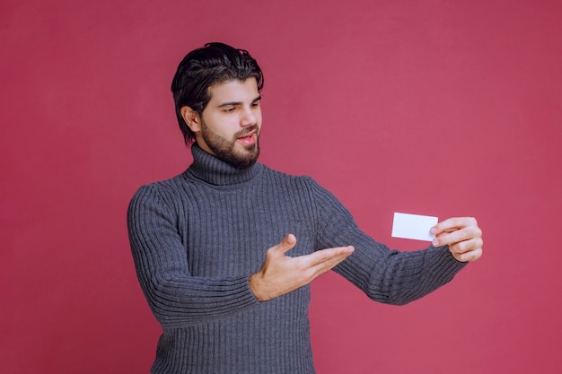 Man holding his business card and pointing at it.