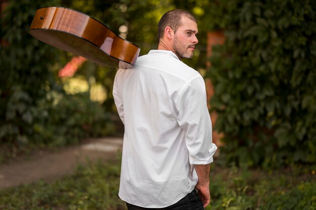 Man holding his guitar on his shoulder from behind shot