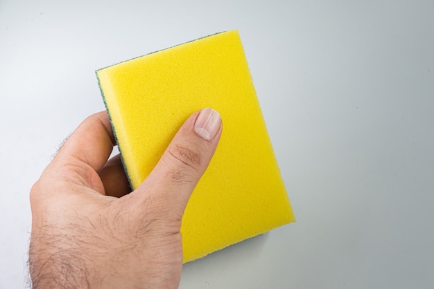 Free Photo man holding kitchen sponge on the white background