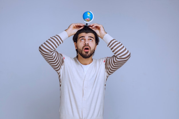 Man holding a mini globe over his head.