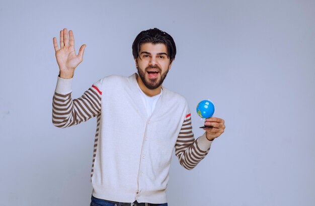 Man holding a mini globe and looks like he studied all the locations and map.