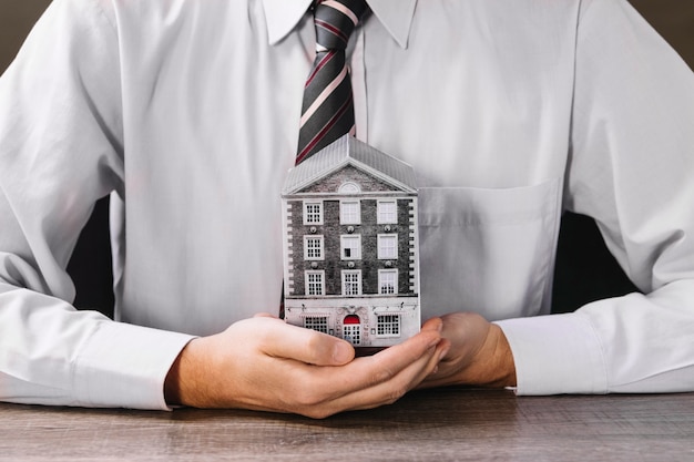 Free Photo man holding miniature house in hands