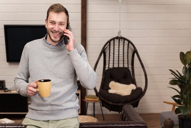 Man holding mug and talking on the phone at home