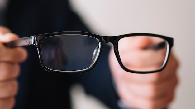 Free Photo man holding a pair of glasses with black frame