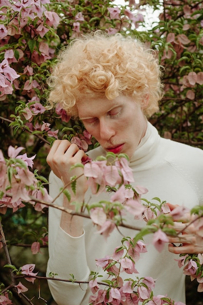 Free photo man holding pink flowers posing in the park