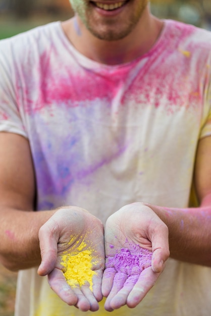 Free photo man holding powder paint in his hands at holi