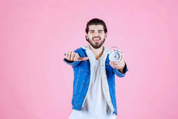 Free photo man holding and promoting an alarm clock