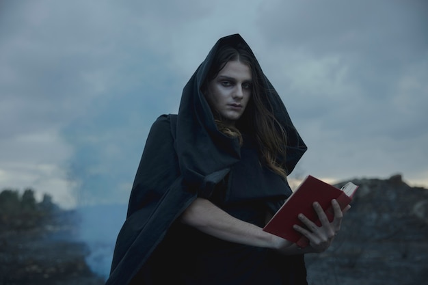 Free Photo man holding a red spell book and looking at camera