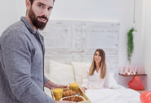 Man holding romantic breakfast on tray 